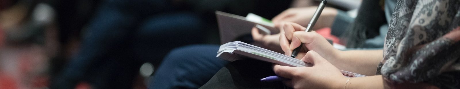 selective focus photography of people sitting on chairs while writing on notebooks